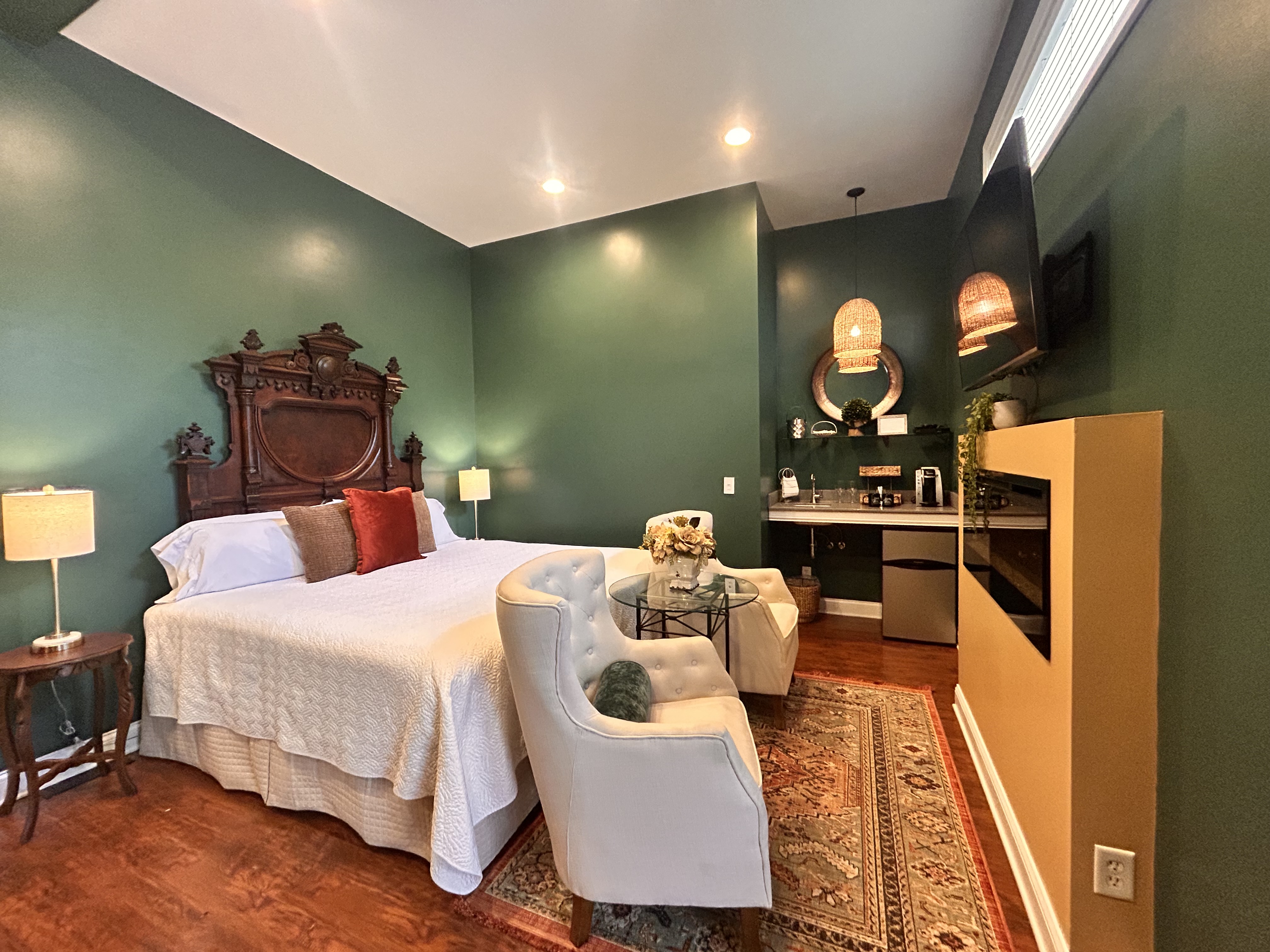 Suite with an Antique king bed, seating area, large fire place and television.