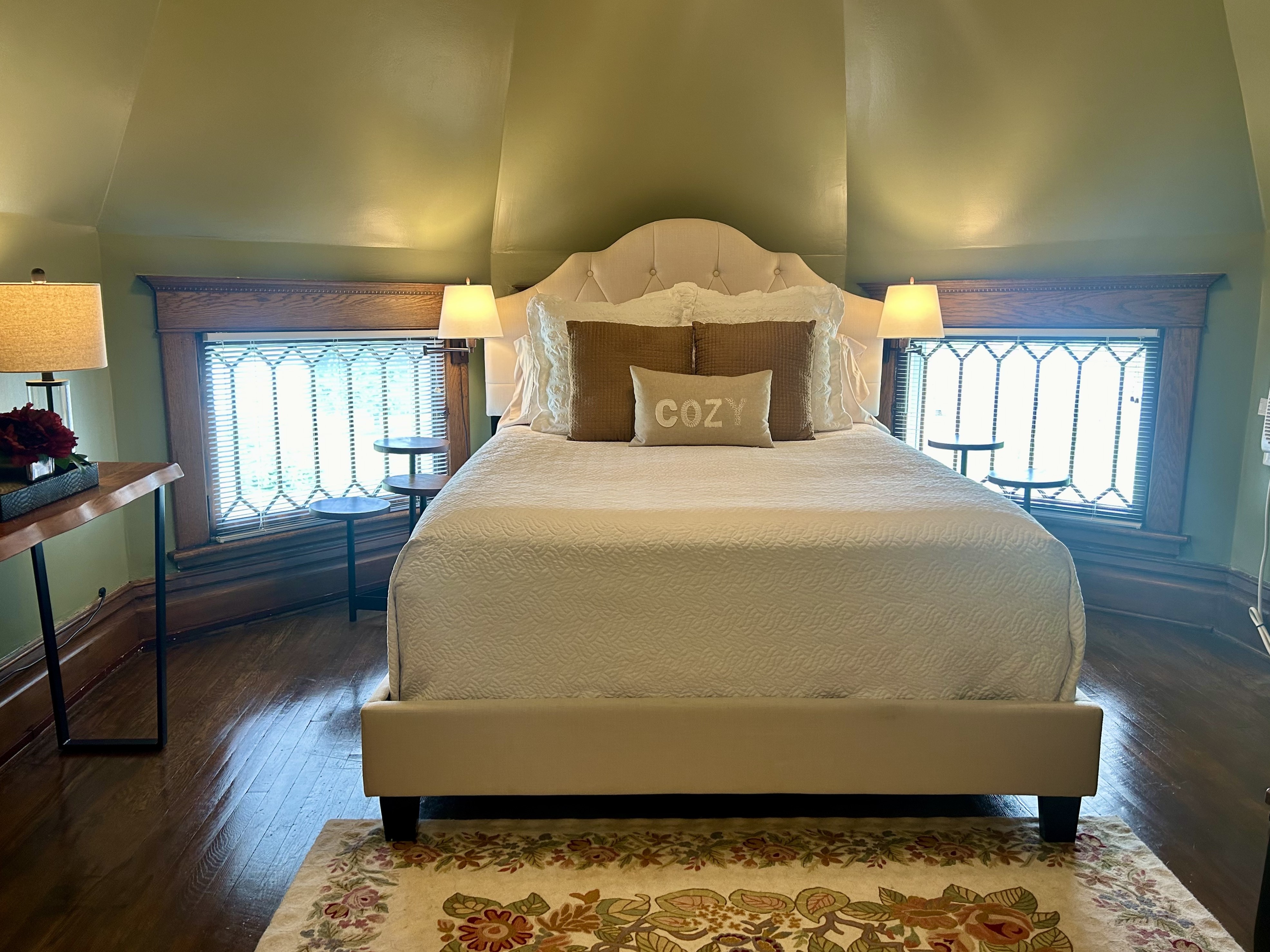 Room inside an eight sided turret, with queen bed, seating area.