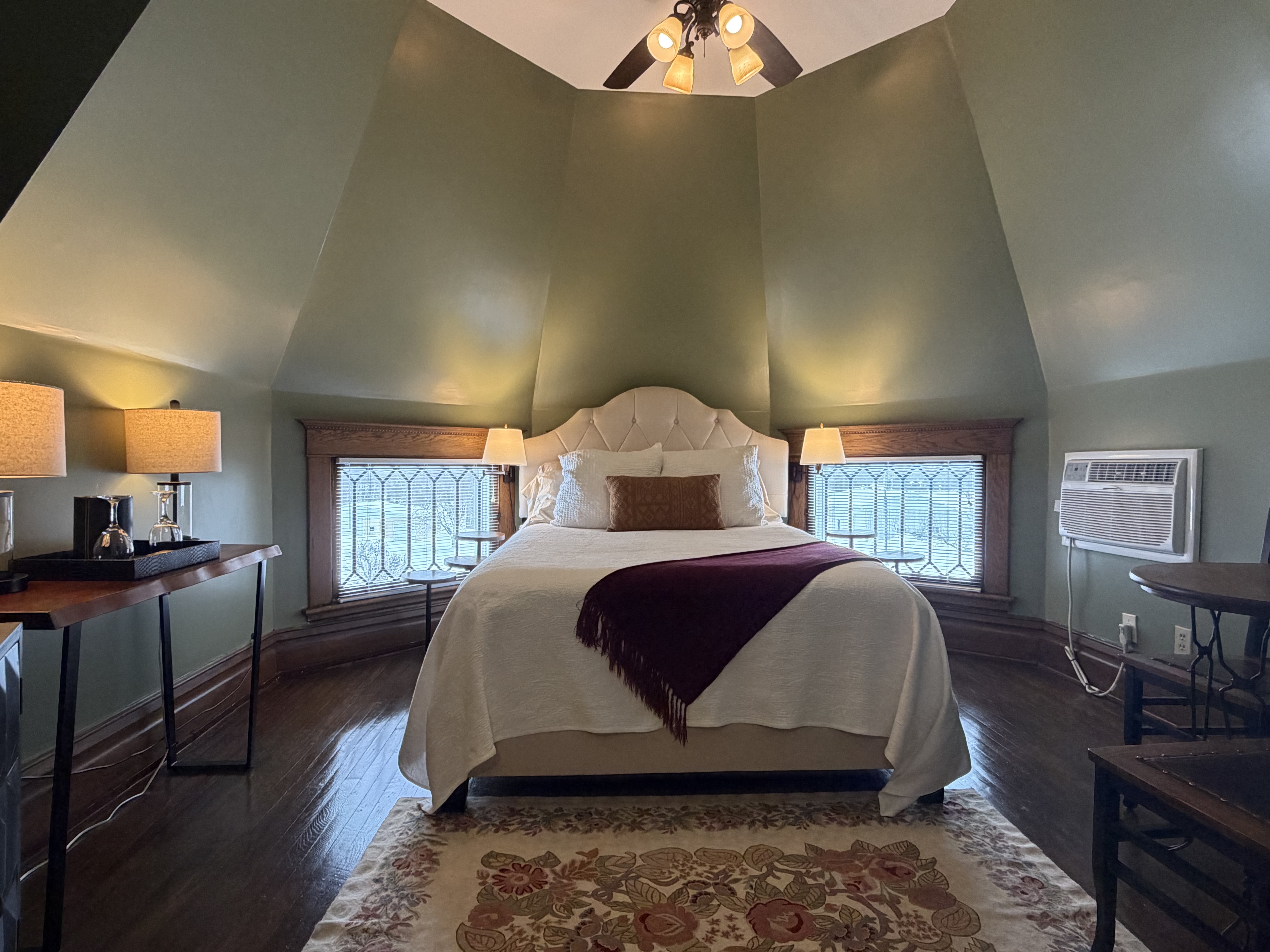 Room inside an eight sided turret, with queen bed, seating area.