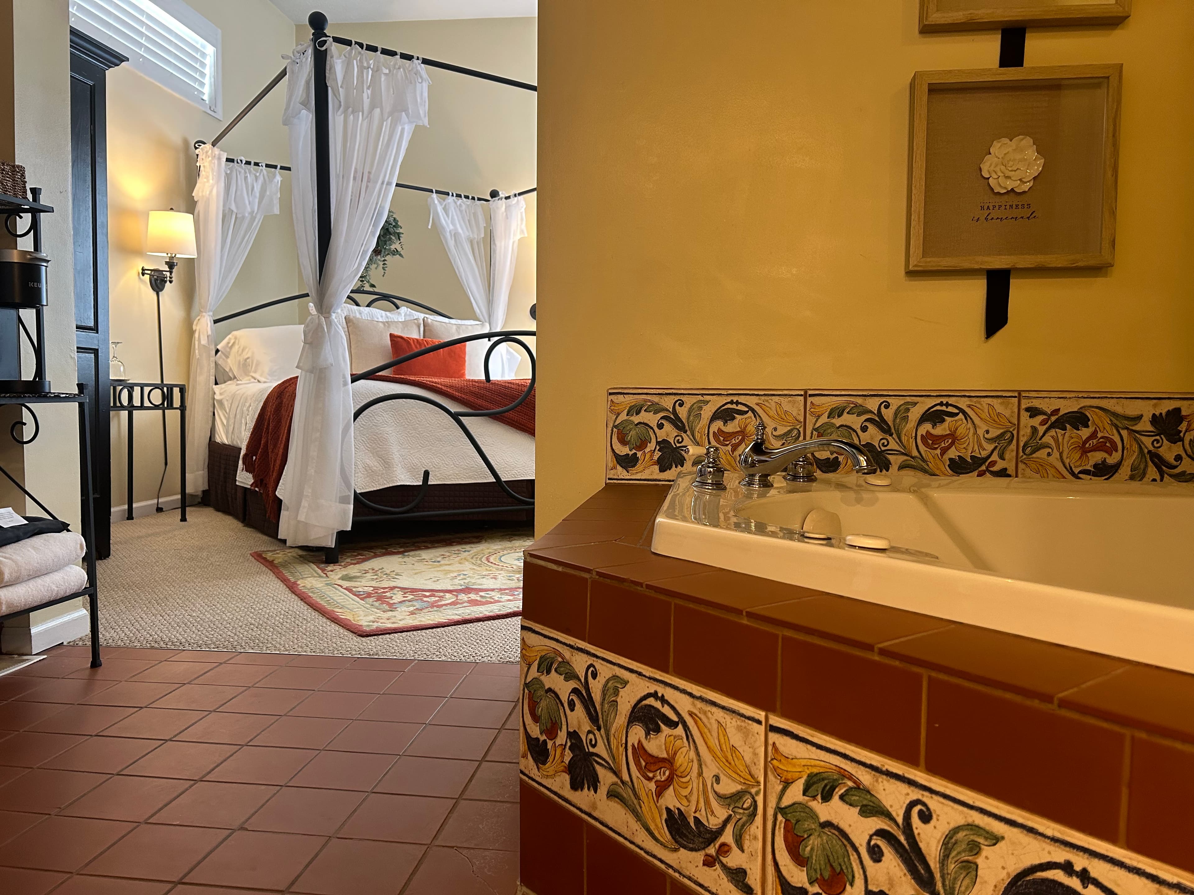 Suite with a king canopy bed, two person jetted tub, and seating area