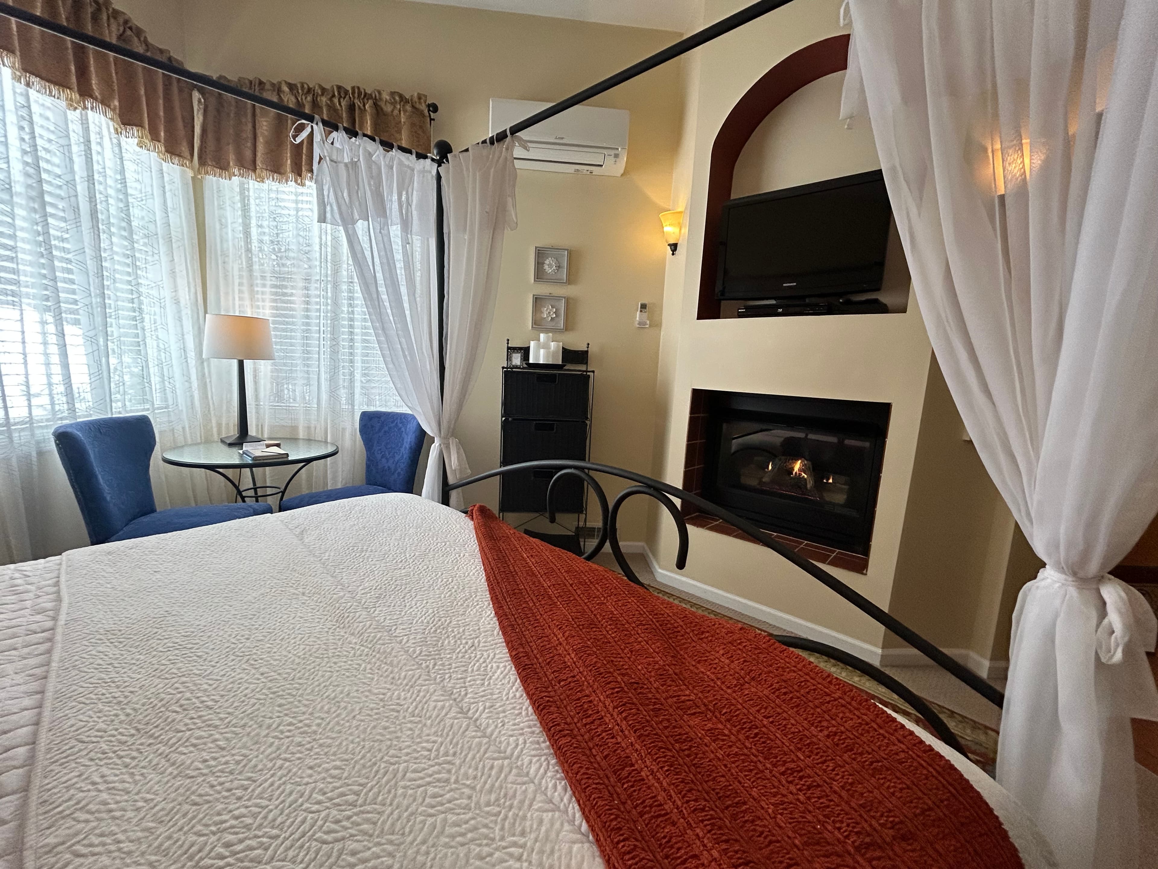 Suite with a king canopy bed with a seating area, fireplace and TV
