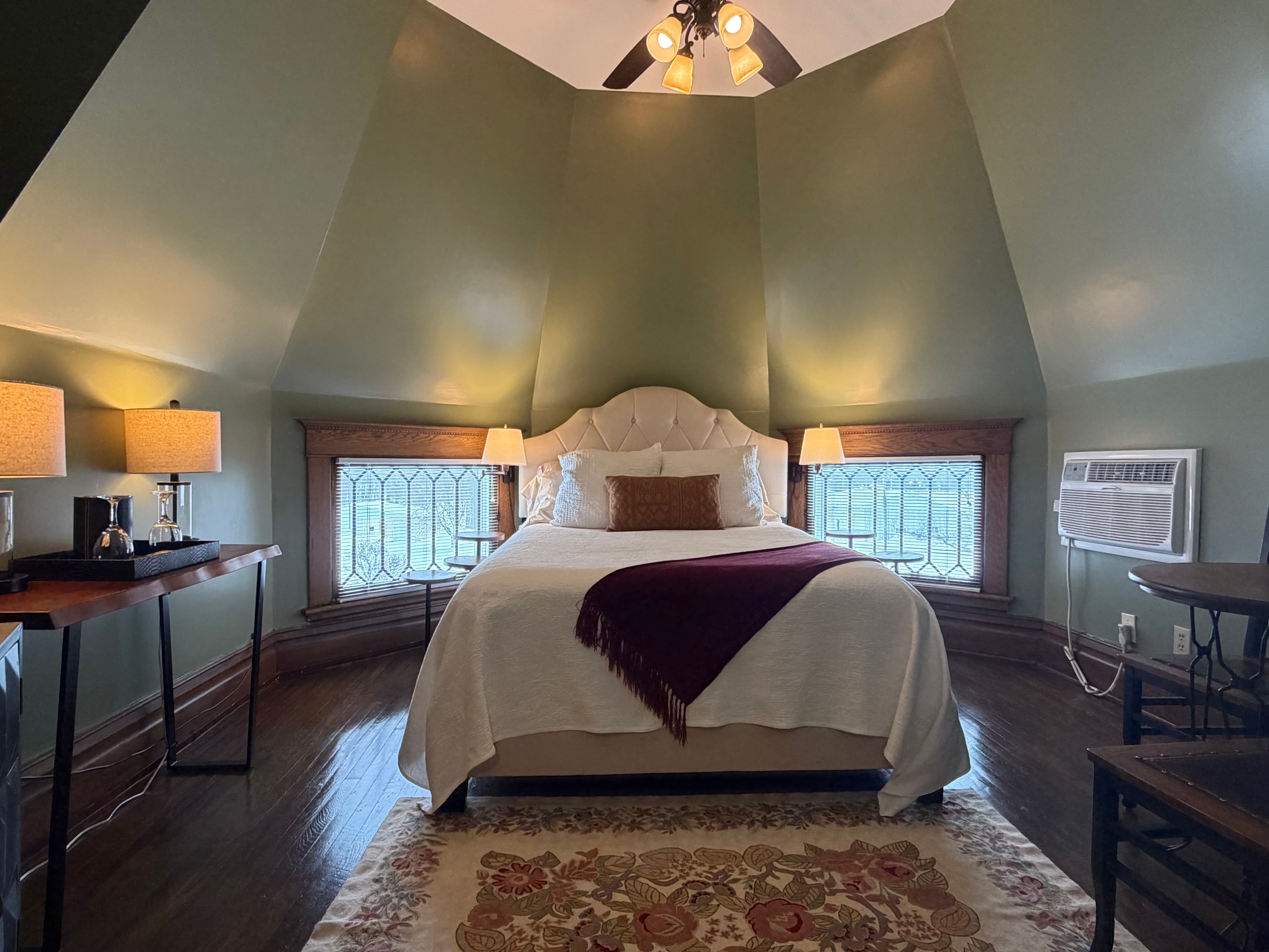 Room inside an eight sided turret, with queen bed, seating area.