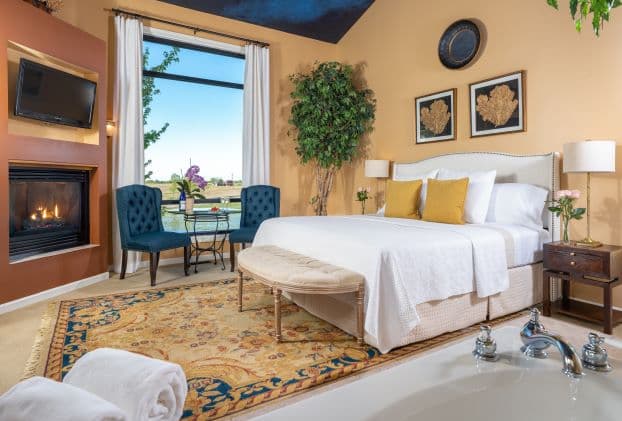 Suite with a king size bed, seating area by the fireplace with a large window over looking the pond.