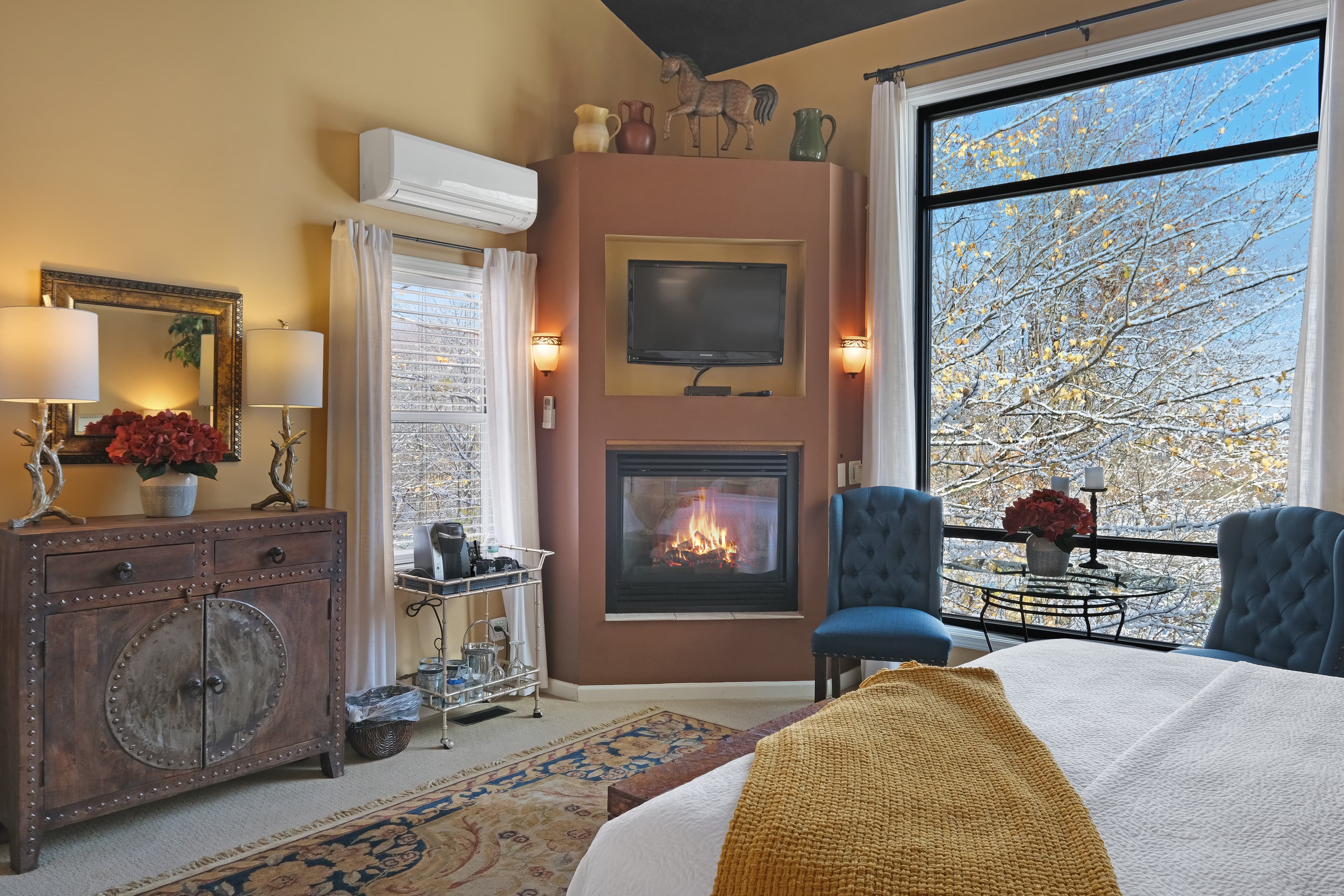 Suite with king size bed with fireplace, seating area, coffee station, and large window.