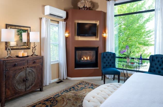 Suite with king size bed with fireplace, seating area, coffee station, and large window.