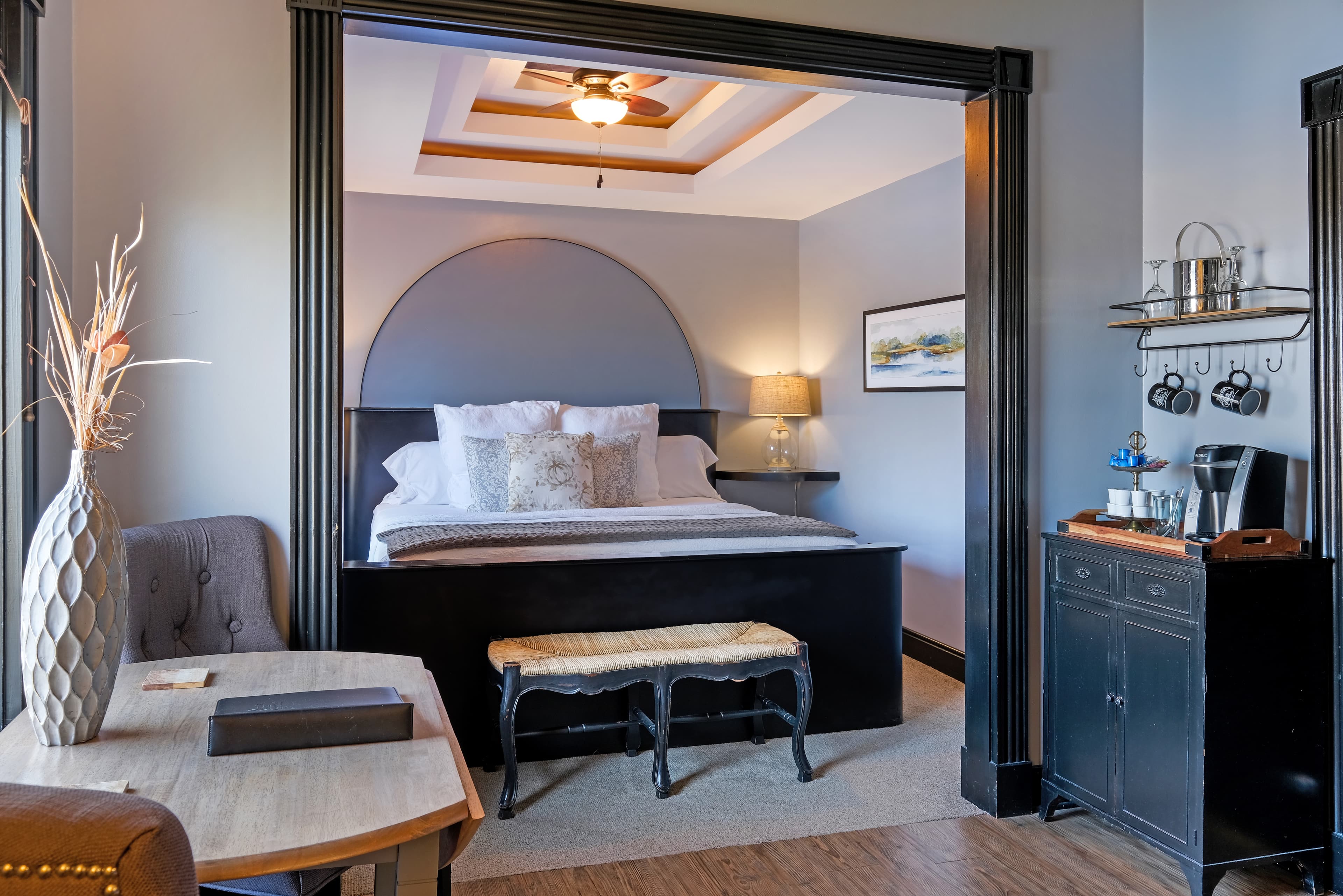 Suite with a king bed, cove ceiling, table and chairs, champagne tray