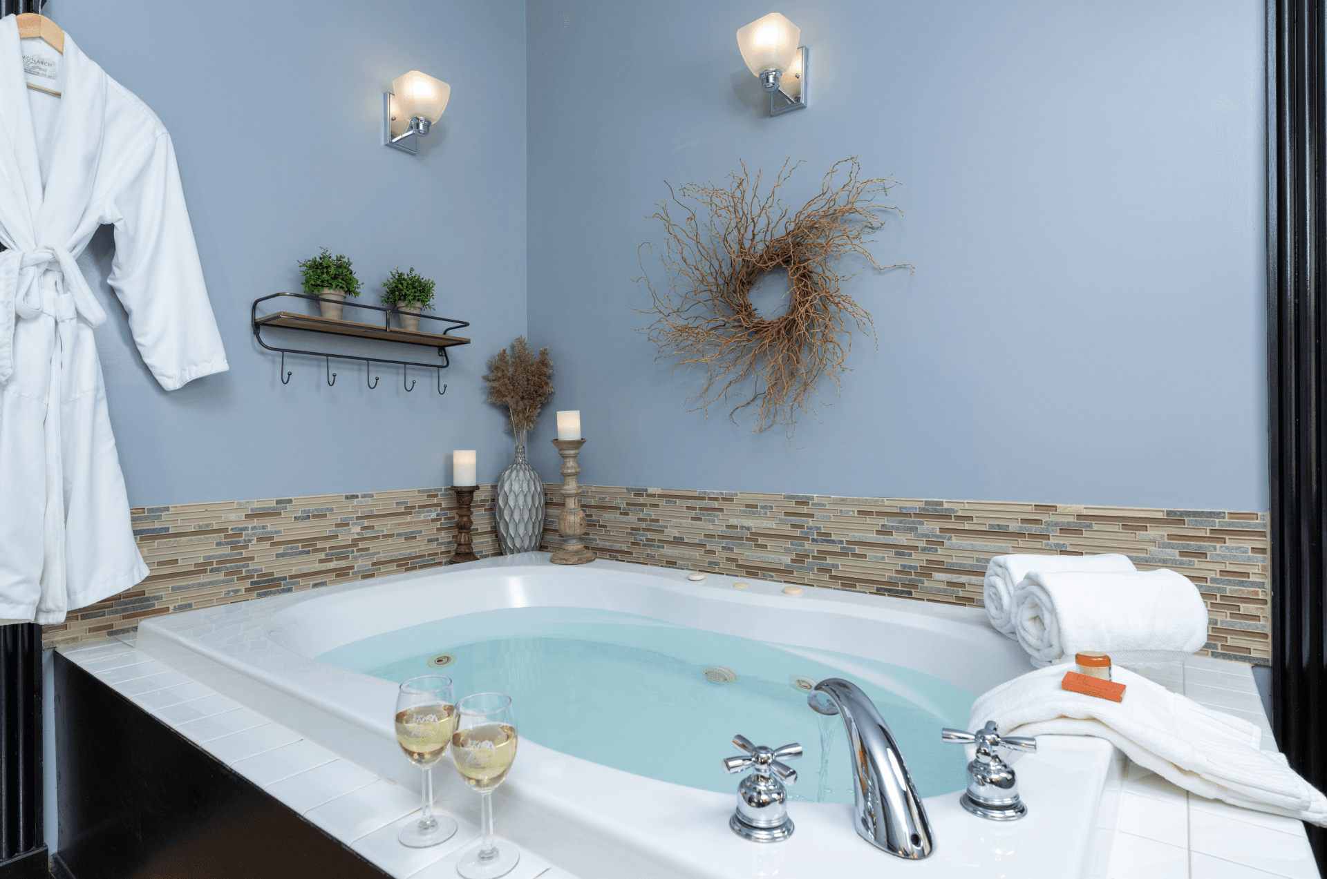 Luxury whirlpool tub with wine glasses, plush towels, and spa decor in a guest suite at Castle in the Country.