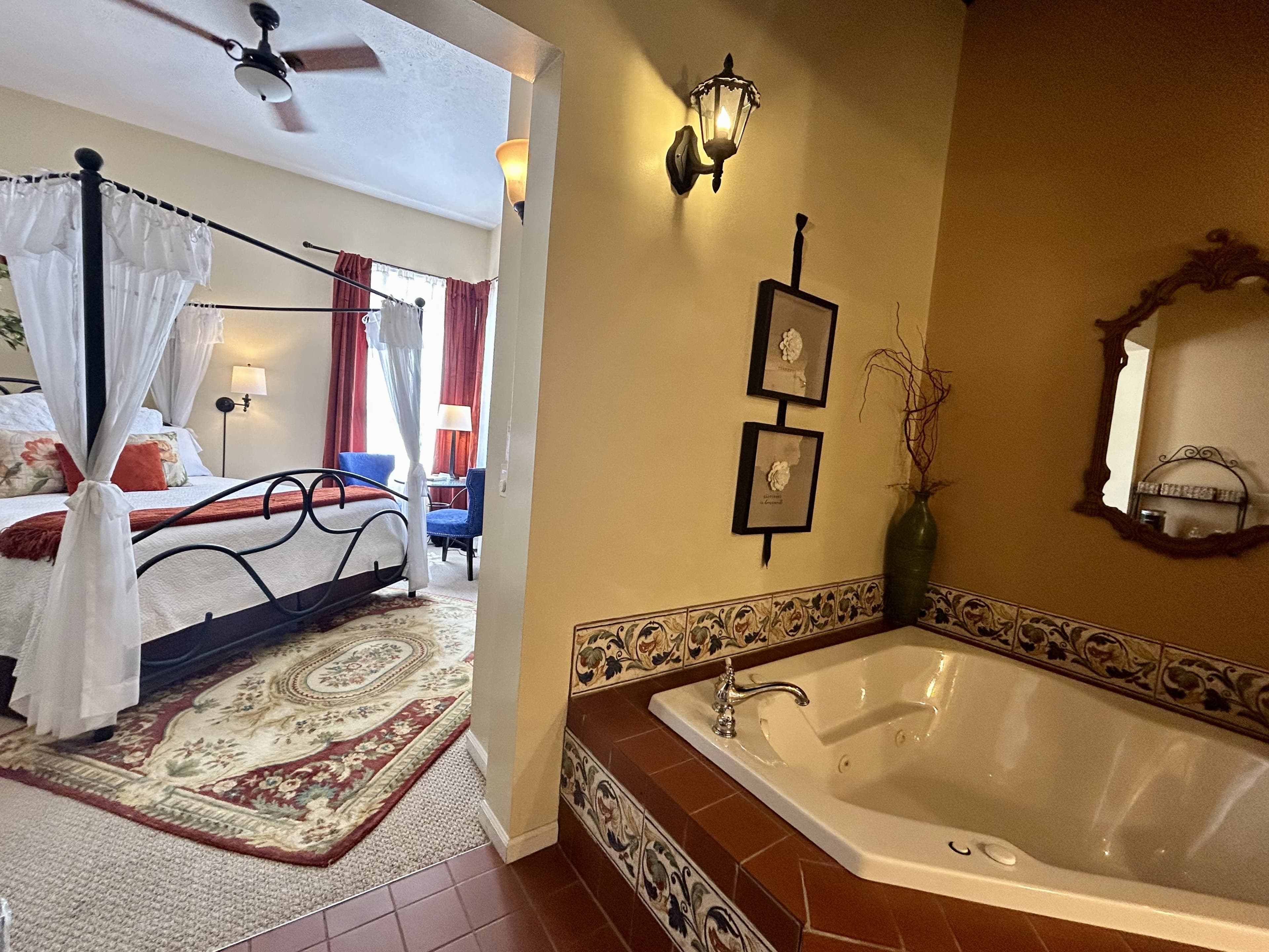 Suite with a king canopy bed, two person jetted tub, and seating area