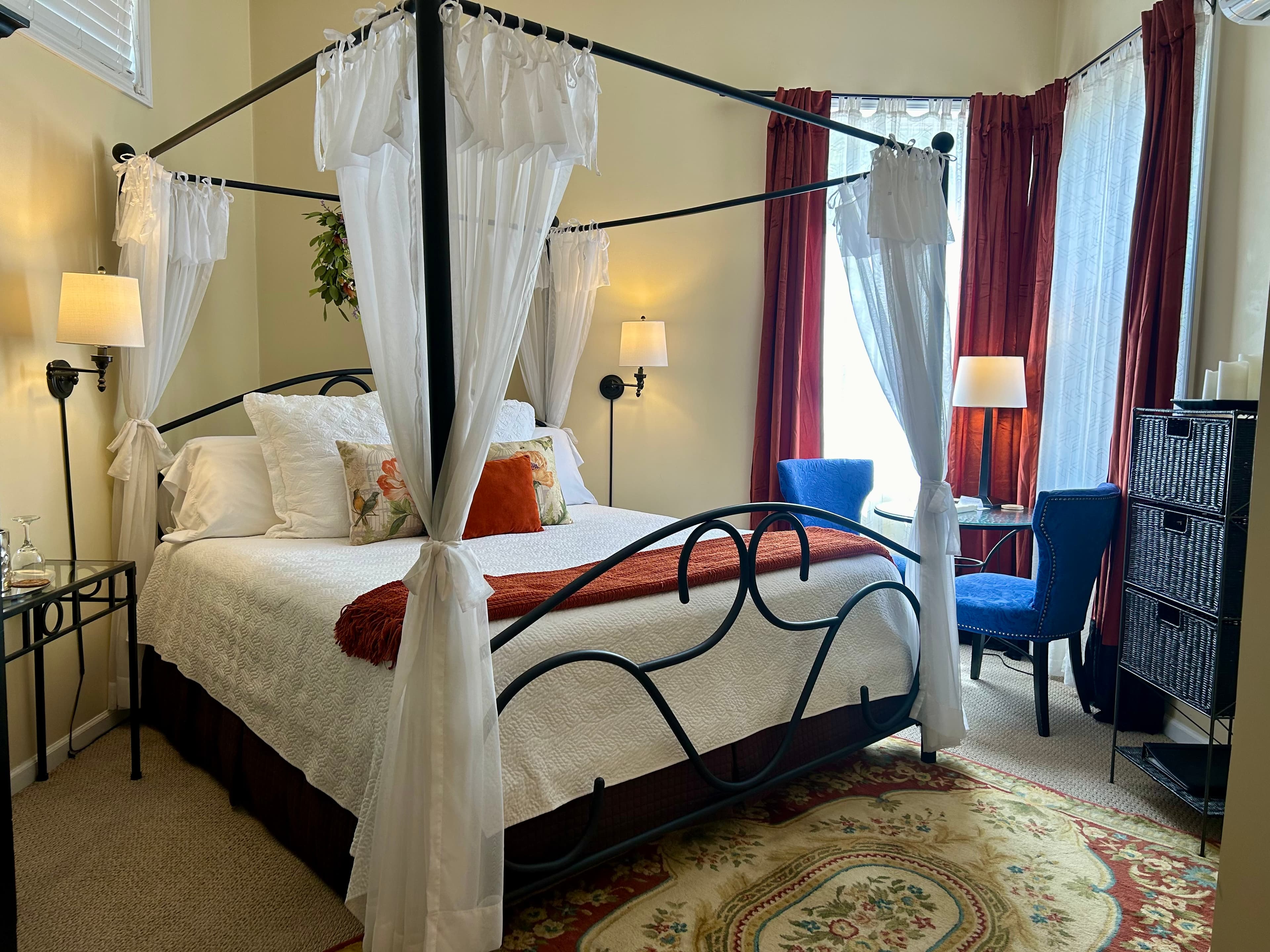 Suite with a king canopy bed, seating area and fireplace