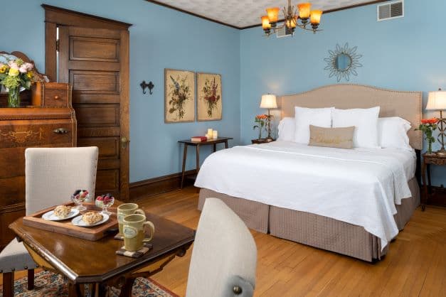 Suite with a king bed, antique furnishings, table/chairs and ensuite bath.