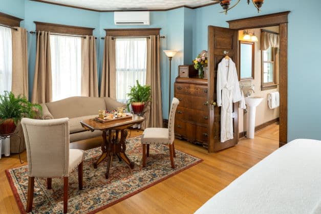 Large seating area with couch and coffee table, patterned oak floors, and antique furniture