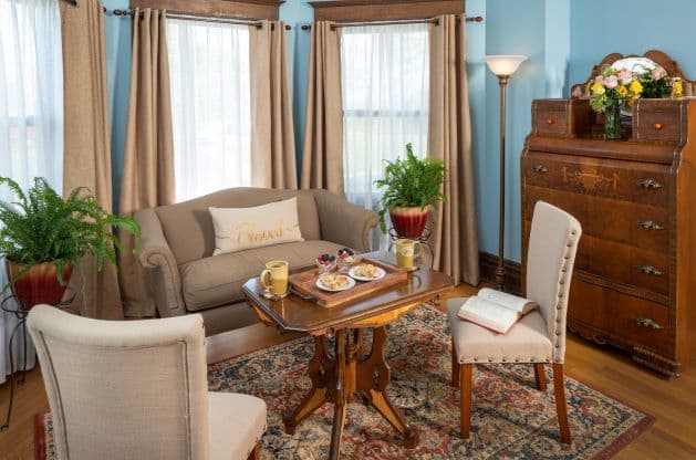 Large seating area with couch and coffee table, patterned oak floors, and antique furniture