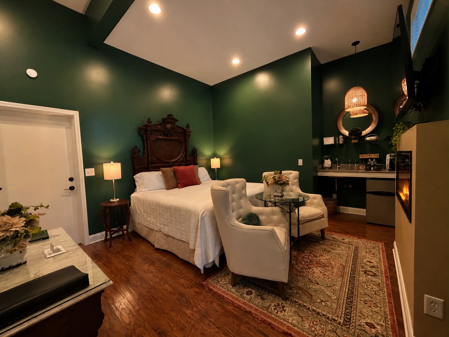 Suite with an Antique king bed, seating area, large fire place and television.