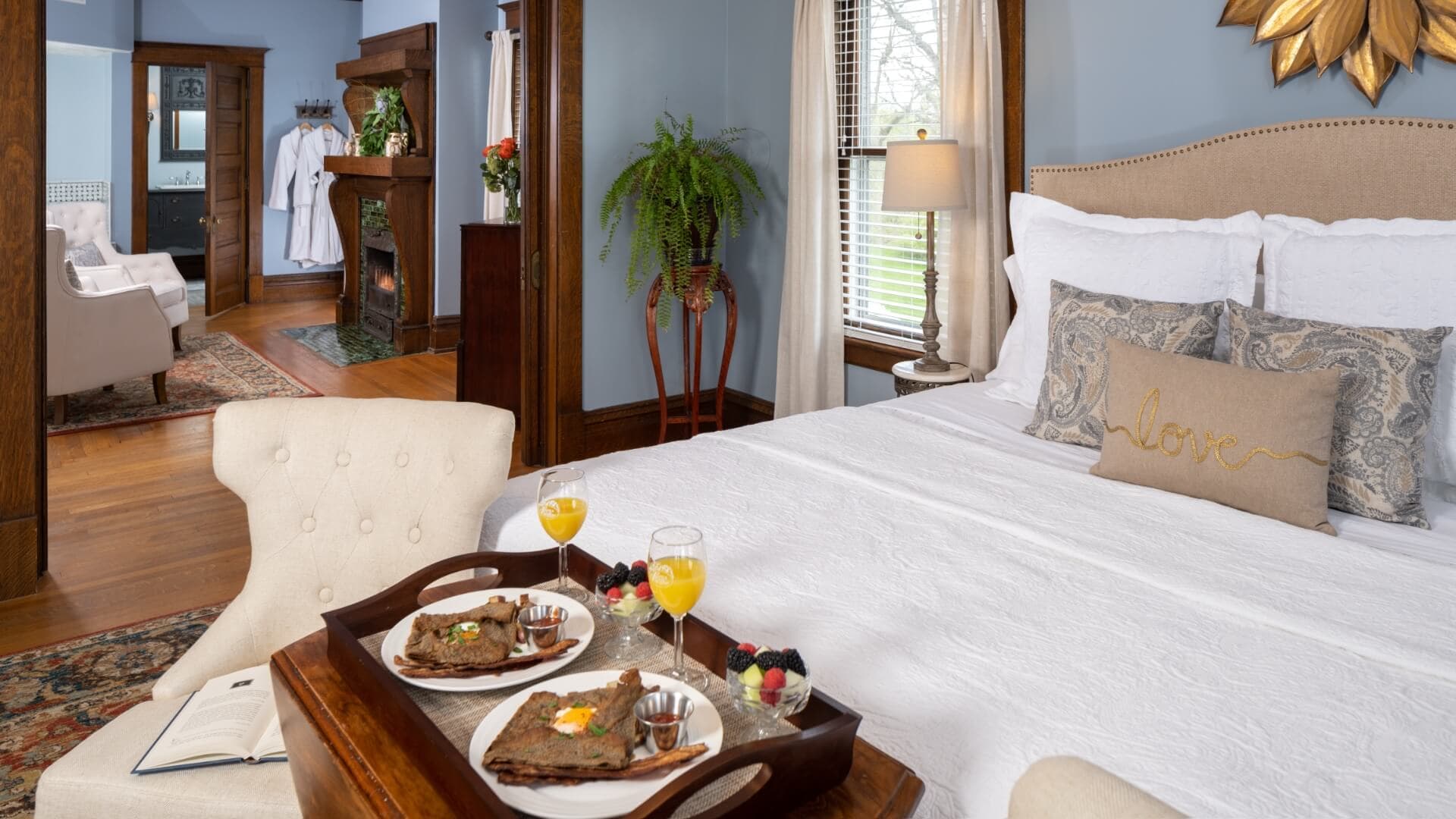 A cozy bedroom featuring a neatly made bed, a tray with breakfast, and inviting decor.