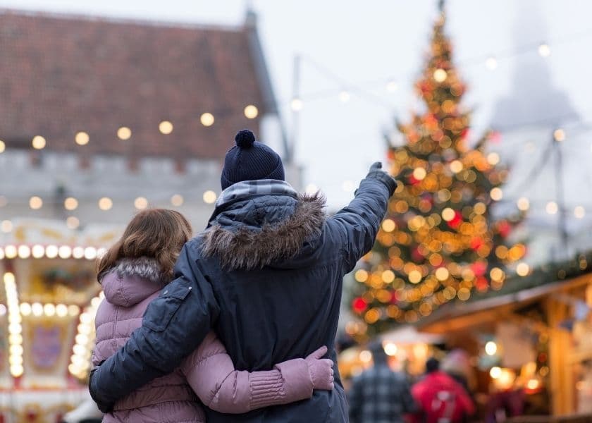 A couple embraces while admiring a decorated Christmas tree in a festive market. A couple embraces while admiring a decorated Christmas tree in a festive market.