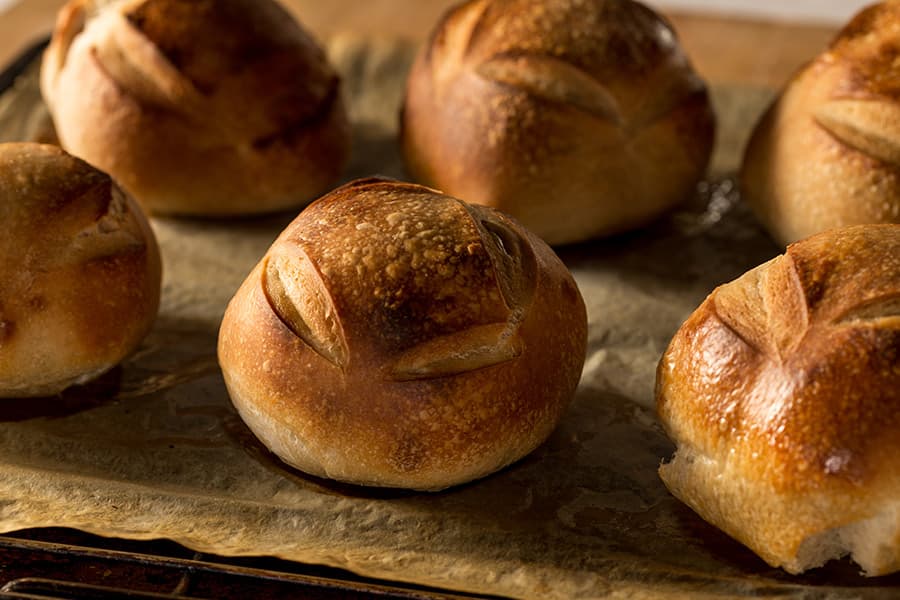 Freshly baked round bread rolls on parchment paper.