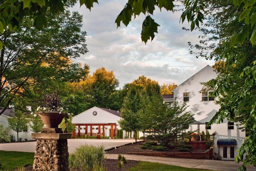 A serene suburban house surrounded by lush greenery and a cloudy sky.