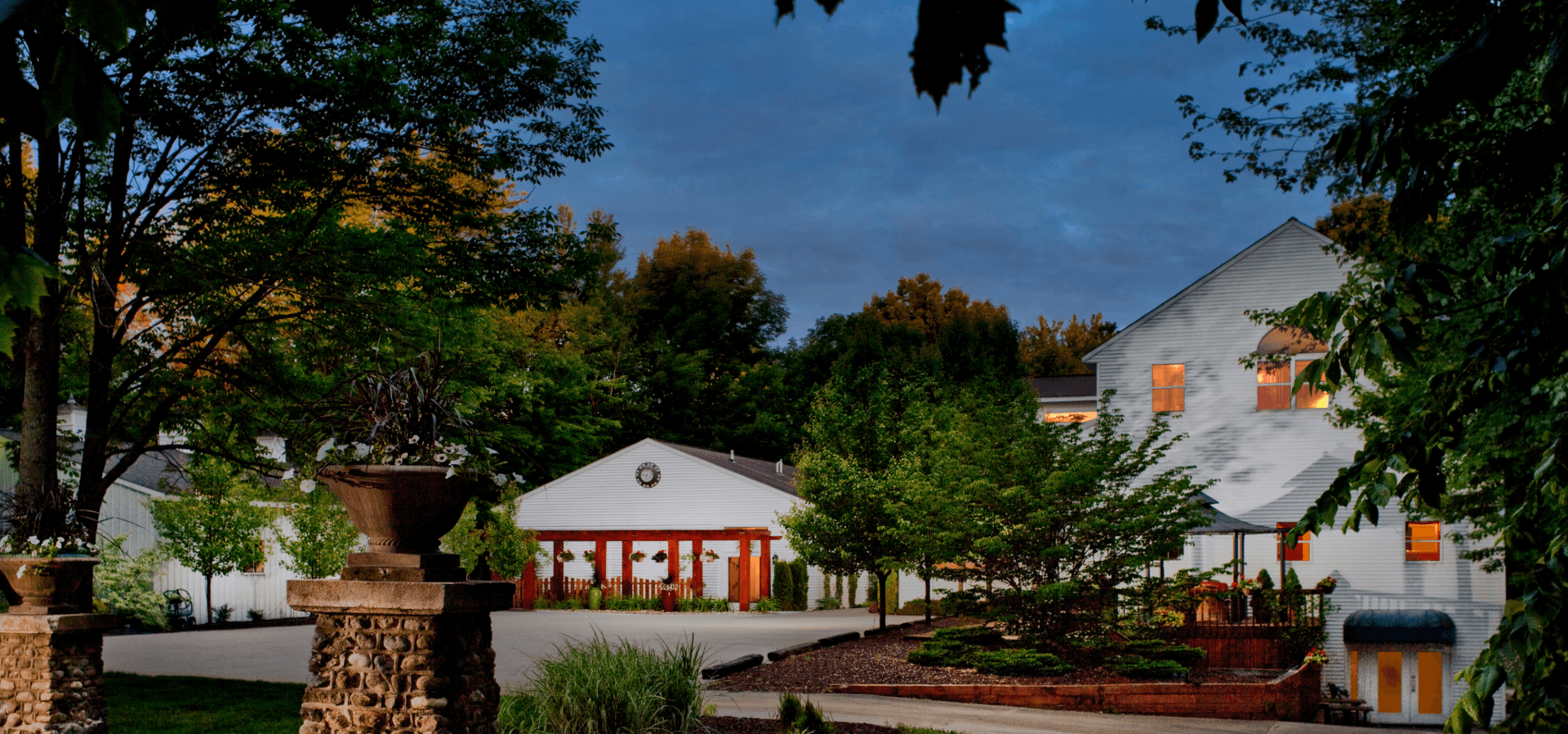 A peaceful suburban scene featuring a landscaped yard and modern white homes under a dusk sky.