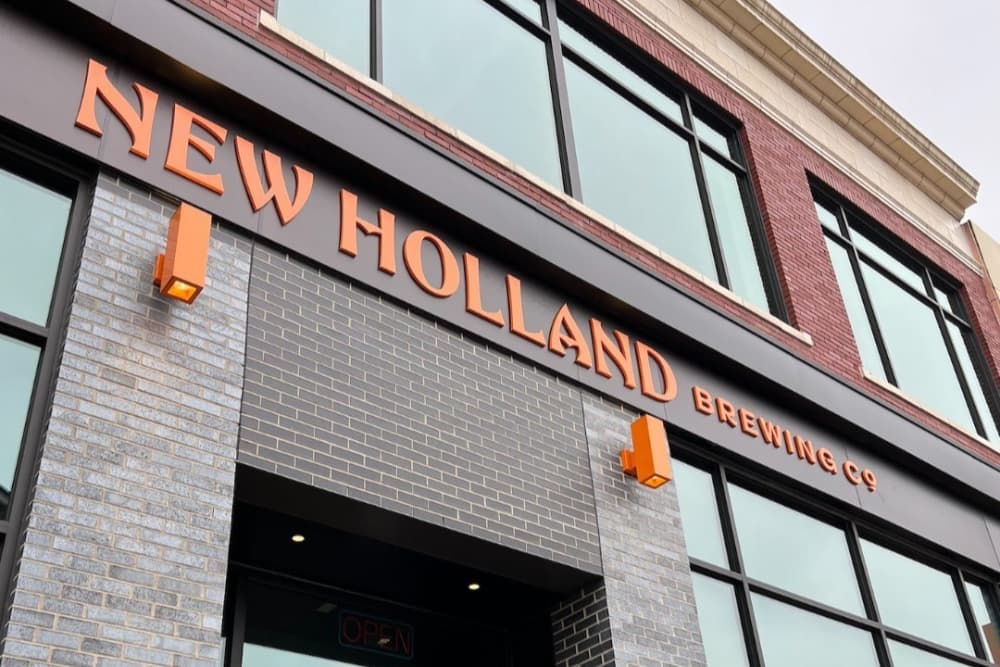 Exterior of New Holland Brewing Co. with orange signage and large windows.
