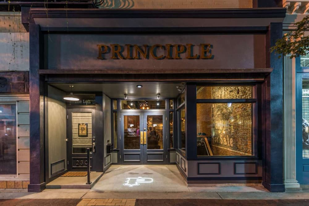 The storefront of "Principle," featuring a prominent sign and illuminated entryway.