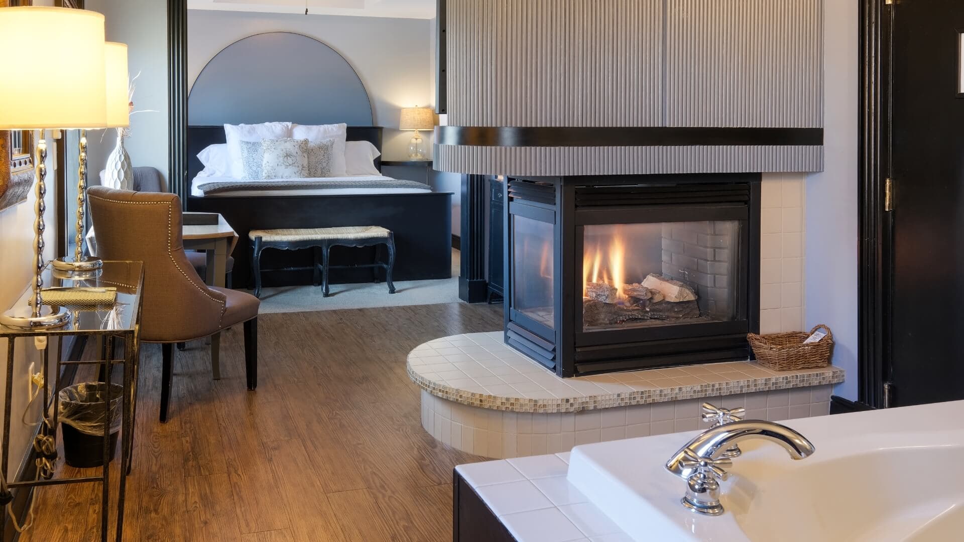 A cozy hotel room featuring a fireplace, a bed, and modern furnishings.