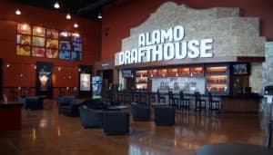 Interior of Alamo Drafthouse featuring a bar and seating area with a modern design.