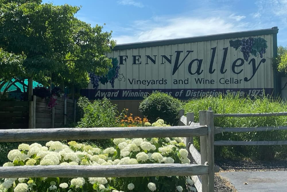 Signage for Fenn Valley Vineyards and Wine Cellar surrounded by greenery and flowers.