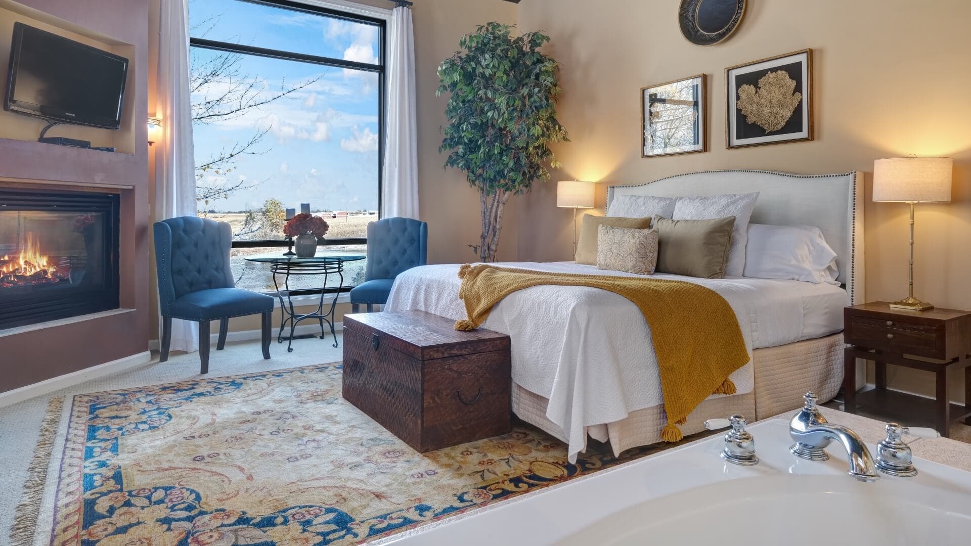 Cozy bedroom featuring a fireplace, large window, and a decorative rug.