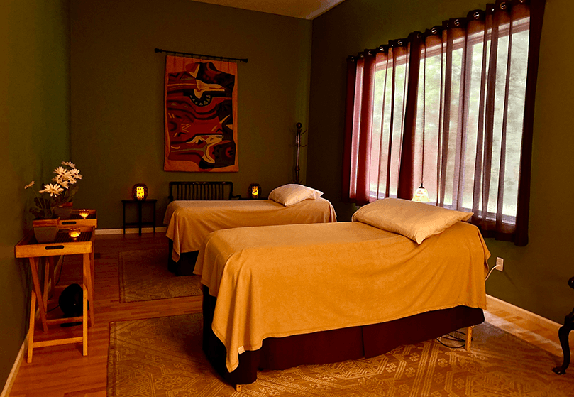 A calming massage room with two massage tables, soft lighting, and natural decor.