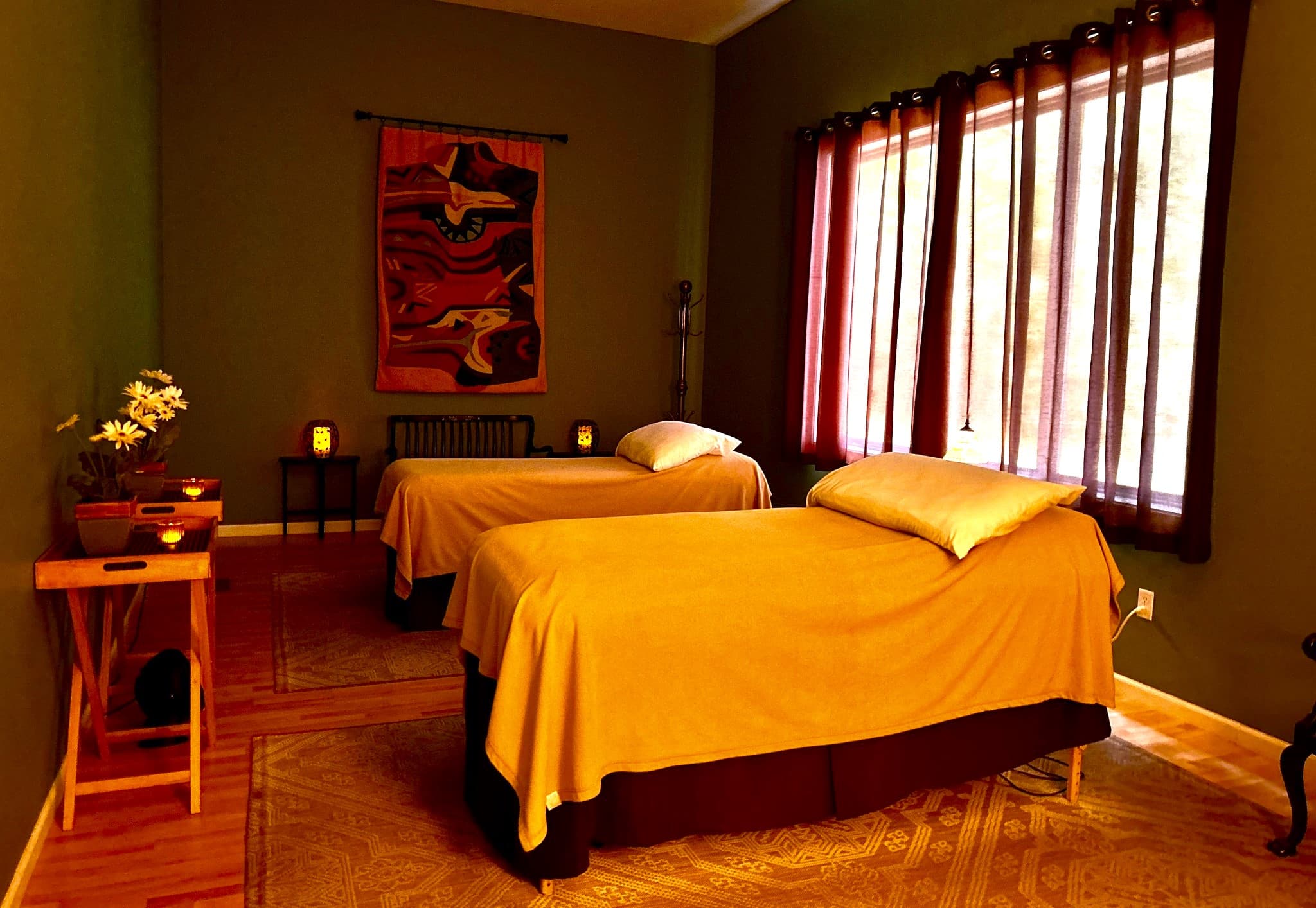A tranquil massage room featuring two treatment tables, soft lighting, and calming decor.