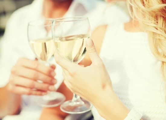 Two people clink glasses of white wine, enjoying a moment together.