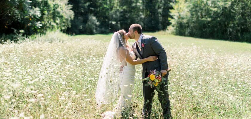 bridal couple kissing in meadow at castle in the country