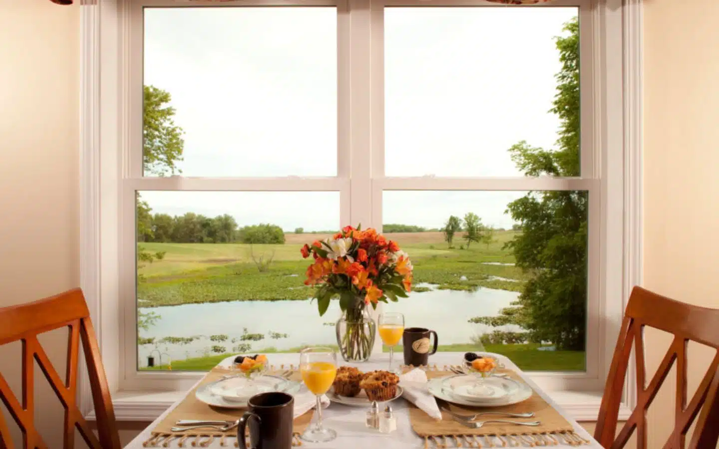 Table for two in the dining room with a view of the water outside of the window.
