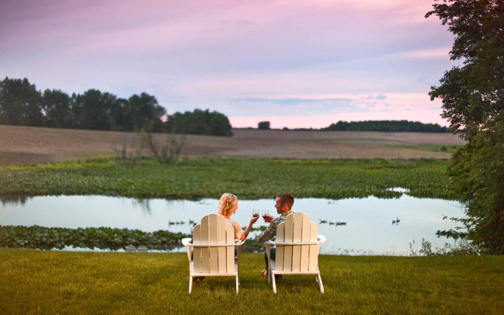 Couple drinking wine by the water at our romantic getaway in Michigan