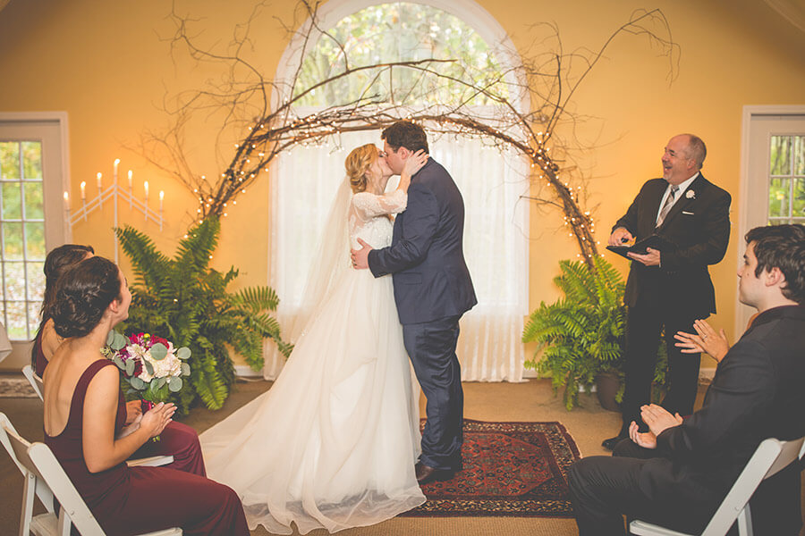 Bride and groom kissing during an indoor wedding ceremony