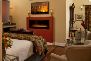 Michigan Honeymoon room - bed, fireplace, chairs, table with champagne on it 