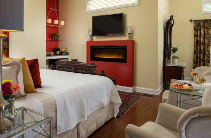 king size bed with large fireplace and television as well as seating area.