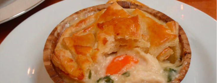 pot pie with carrots and green beens in brown bowl sitting on white plate dinner salad and crystal water goblet
