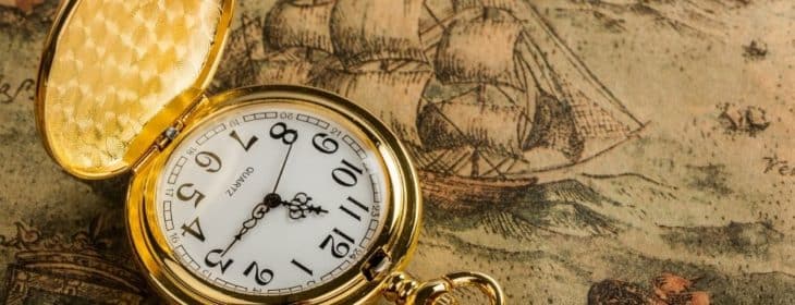 Antique pocket watch propped open on an antique drawing of a ship
