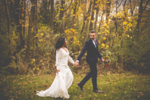 Wedding couple in the fall walking on grass with leaves on ground