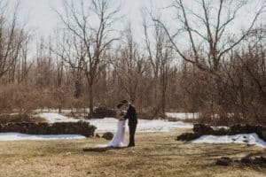 wedding couple pose inside stone foundation in winter with snow in background