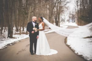 wedding couple posing on path in winter with snow on ground