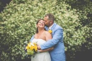 wedding couple embrace in front of willows