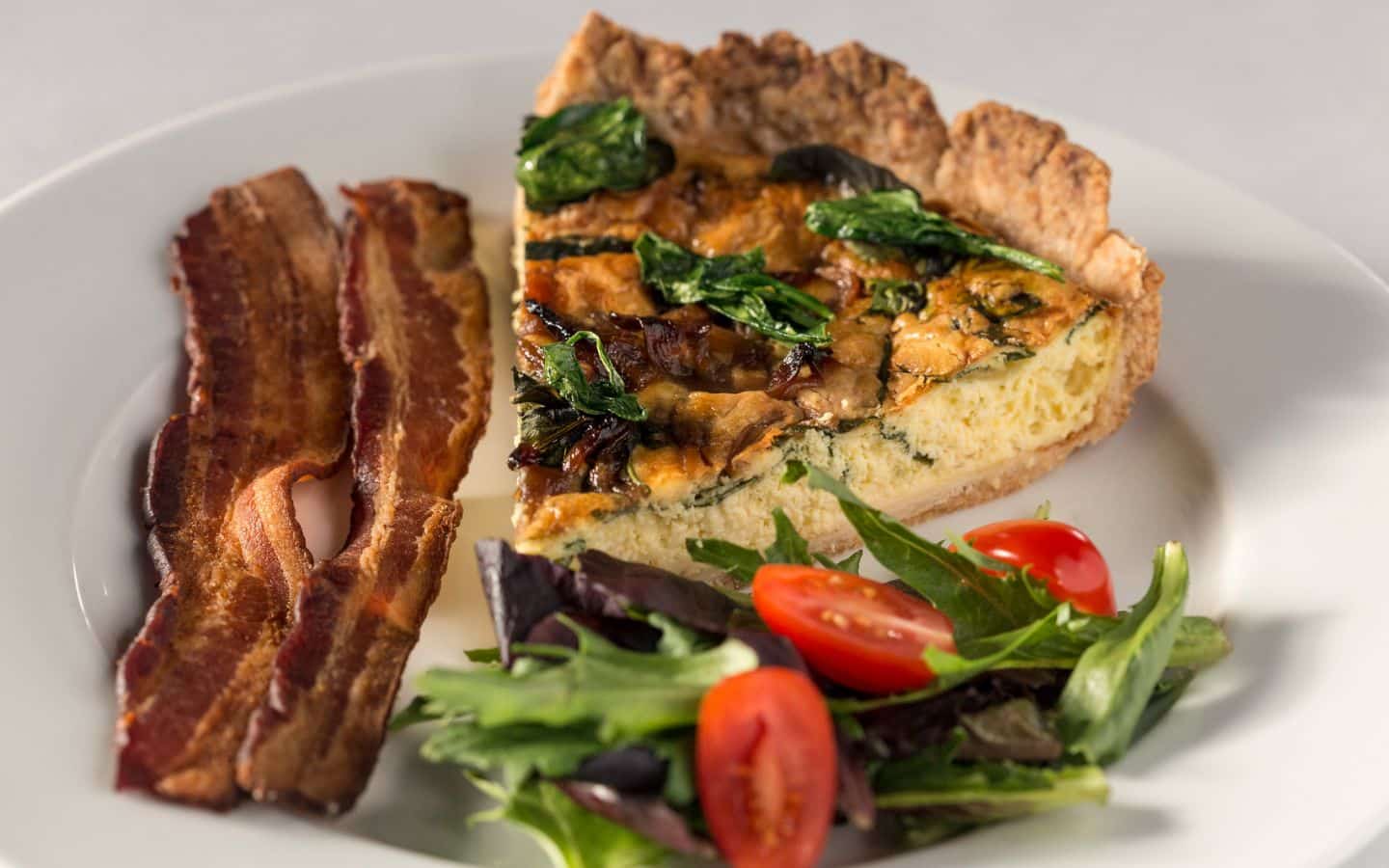Breakfast plate with quiche, salad and bacon.